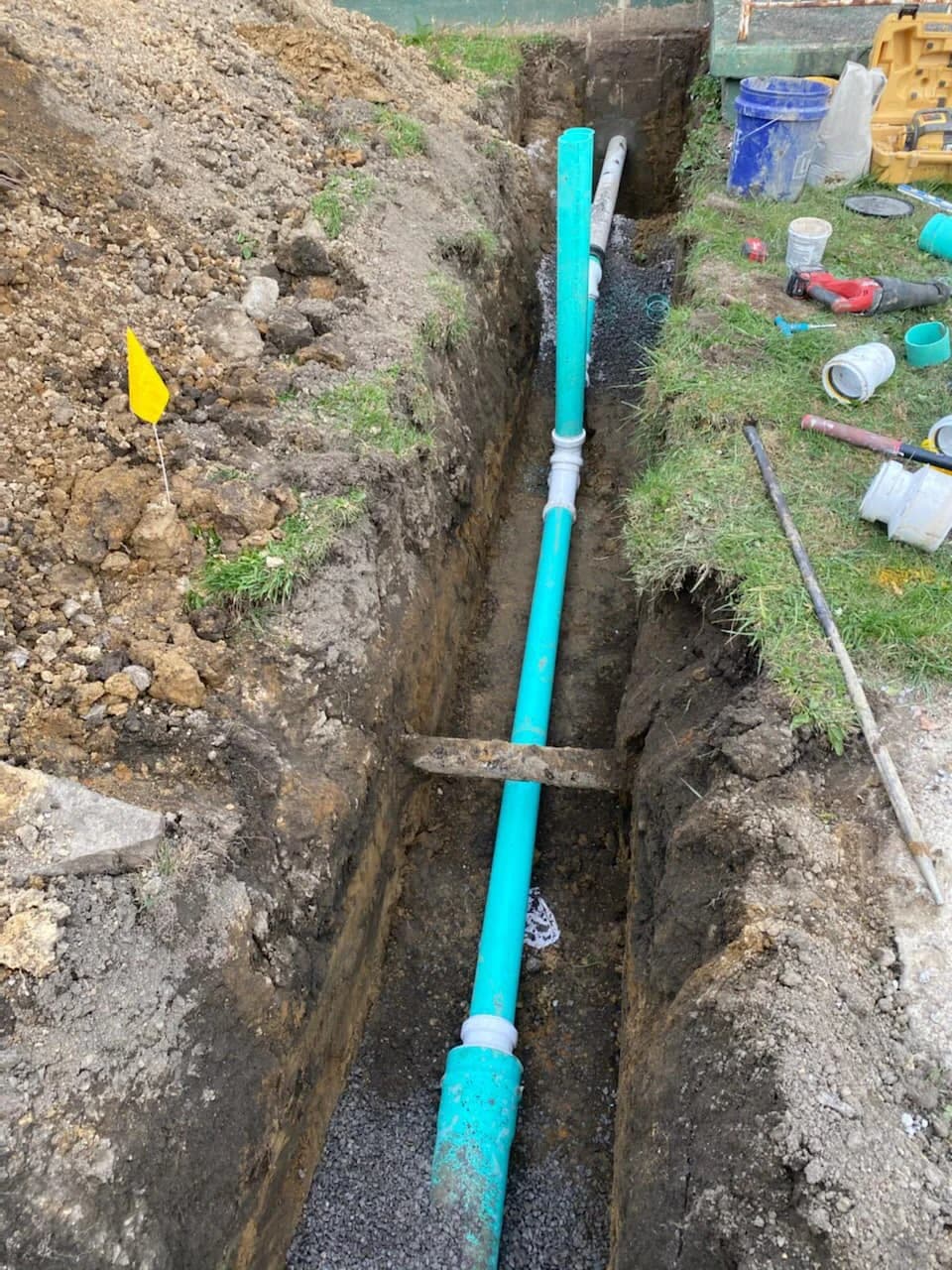 Green PVC sewer with cleanouts and utility flag in WNY yard trench